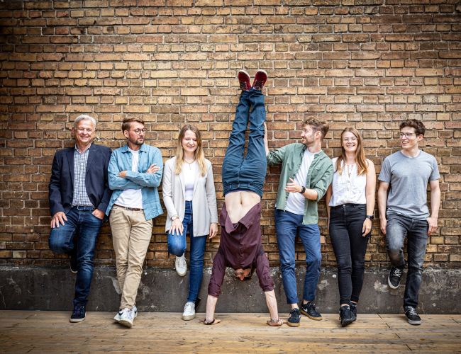 Das sun concept Team, angelehnt an einer Backstein Mauer